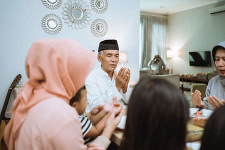 asian muslim family praying before having their iftar meal during ramadanの写真素材
