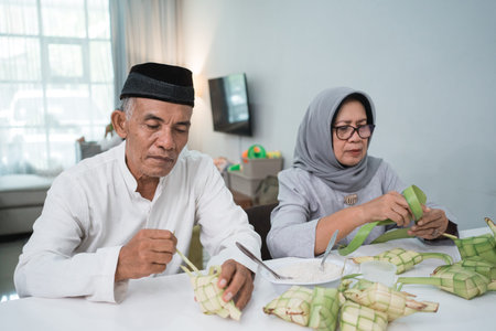 two mature couple making ketupat for eid fitri mubarak