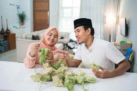 beautiful muslim couple asian making ketupat rice cake at homeの写真素材