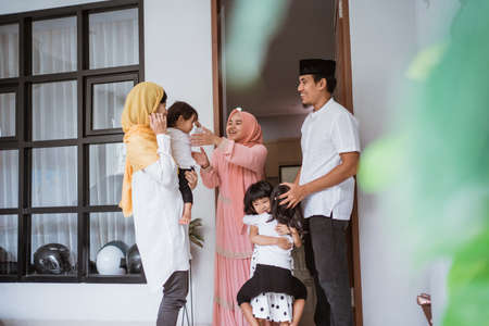 excited family visiting friend during eid fitri mubarak at homeの写真素材