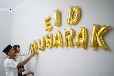 father and daughter muslim decorating eid mubarak letter made of baloon decorationの写真素材