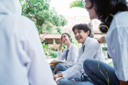 couple of high school students laugh during discussion and chat with a group of friendsの写真素材