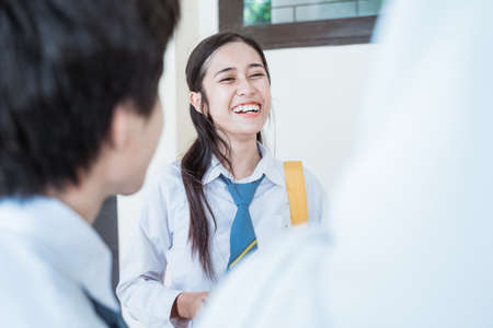 close up of smiling beautiful girl and friends in high school uniform discussingの写真素材