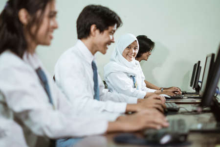 Indonesian high school students using computer pc with their friends studying in a computer lab roomの写真素材