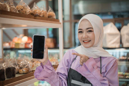 muslim woman with hijab show her mobile phone screen to cameraの写真素材