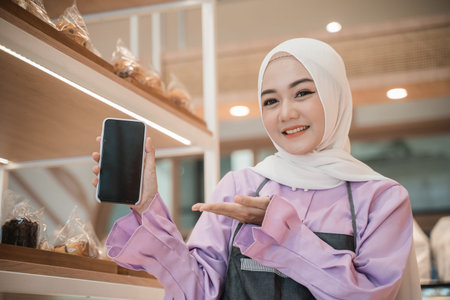 muslim woman with hijab show her mobile phone screen to camera