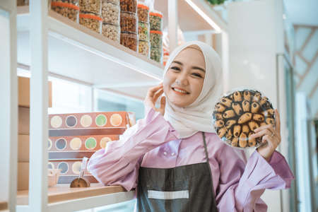 muslim woman holding some cake for eid mubarak in her storeの写真素材
