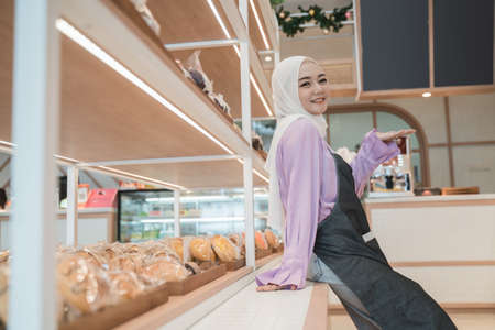 beautiful young woman hijab smiling proudly at her shopの写真素材