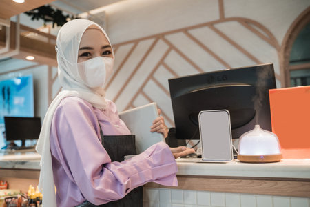 muslim asian woman working using pc while wearing medical face mask