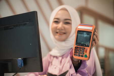 attractive cashier muslim showing edc machine to camera