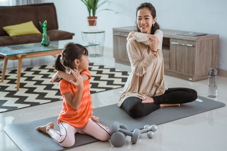 mother doing yoga exercise at at home with her daughter togetherの写真素材