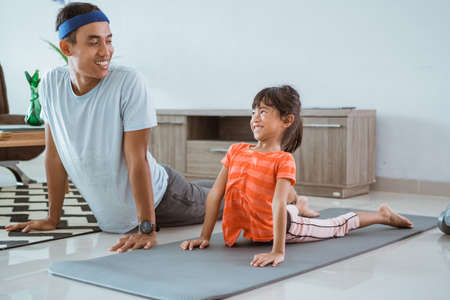 father and daugther exercising together at homeの写真素材