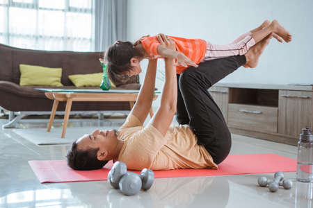 father use his child as weight for lifting exercise at homeの写真素材