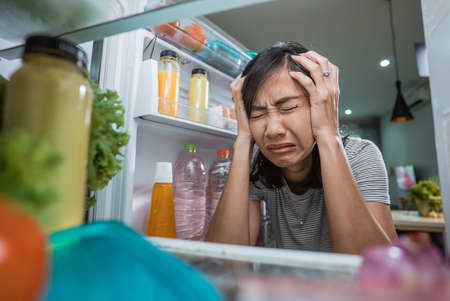 unhappy young asian woman looking inside the fridge. shoot from the insideの写真素材