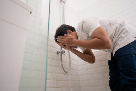 portrait of young Muslim man perform ablution (wudhu) before prayer at homeの写真素材