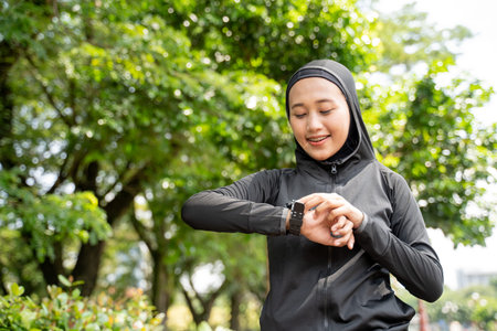 beautiful muslim woman monitoring her heart rate on smart watch during exercising outdoor