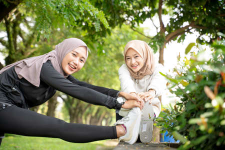 muslim woman friend athlete stretching her leg outdoor togetherの写真素材
