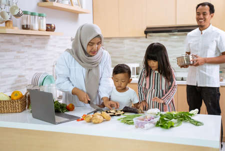 muslim family with two children cooking together at home preparing for dinner and iftar break fastingの写真素材