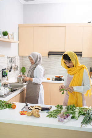 two attractive young muslim woman preparing iftar dinner together. Ramadan and eid mubarak cooking in the kitchenの写真素材