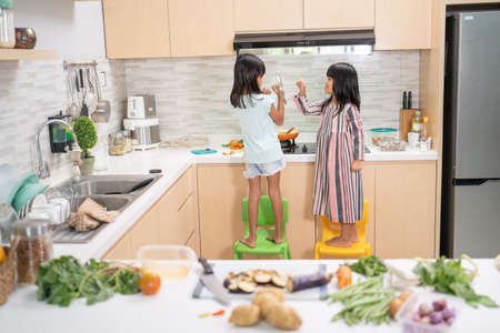 portrait from the back of two little kid cooking in the kitchen and have funの写真素材