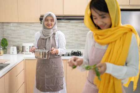 beautiful two muslim woman enjoy cooking dinner together for iftar breaking the fast on ramadan in the kitchenの写真素材