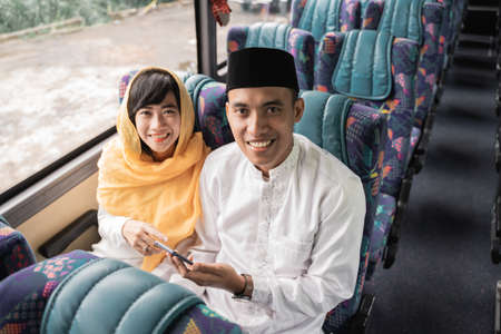 muslim couple travel by bus during eid mubarak holiday to meet family at homeの写真素材