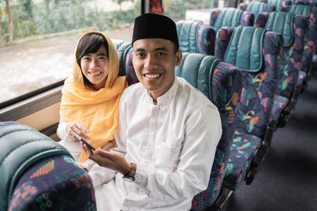 muslim couple travel by bus during eid mubarak holiday to meet family at homeの写真素材