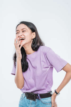 attractive Asian young girl laughing while covering her mouth isolated on a white backgroundの写真素材