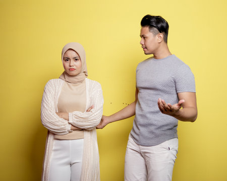 two young couples in a problem. a man asking women what something wrong isolated on yellow backgroundの写真素材