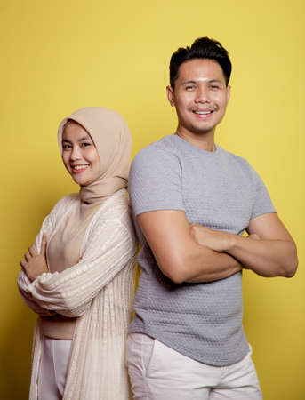 close up hijab women and men smiling crossed arms looking at camera isolated on a yellow backgroundの写真素材