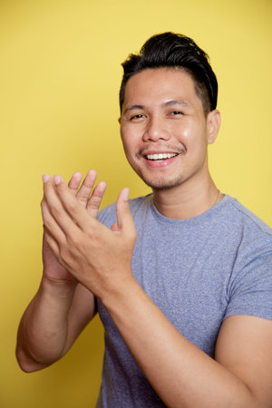 close up man smile expression very spirit with applause hand isolated on a yellow color background