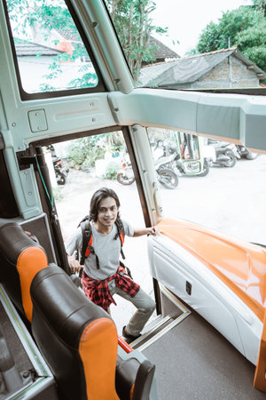 a man wearing a backpack through the bus door when getting into the busの写真素材