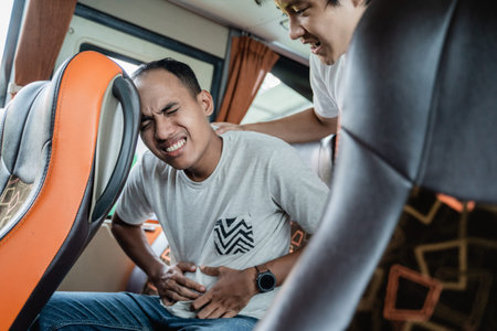 a man with a stomachache and his friend helped while sitting on a bus seat while traveling