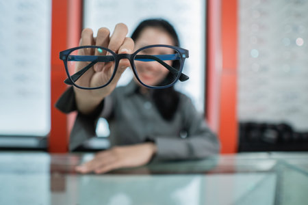 a woman holds the glasses of choice she chooses at the eye clinic