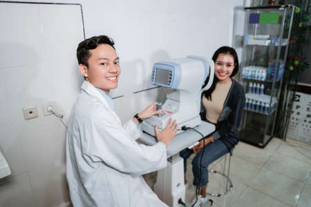 a male doctor has finished examining a female patients eyes using an eye computer at a clinicの写真素材
