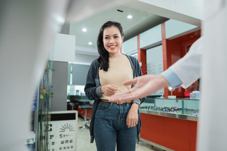 a beautiful woman walks when the waiter welcomes her in with a hand gesture at the eye clinic