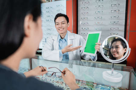 A male doctor is showing a color test board which is one of the basics of eye examinations in an eye clinicの写真素材