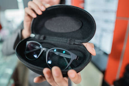 hand holds the glasses in the eyeglass holder as the customers hand selectsの写真素材