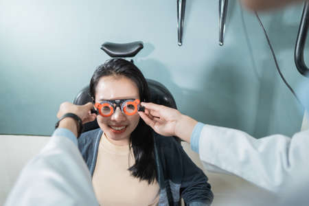 a doctor is using measuring glasses to a female patient in a room at an eye clinicの写真素材