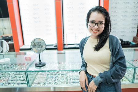 a beautiful woman wearing glasses of her choice and posing in front of an eyeglass window at an eye clinicの写真素材