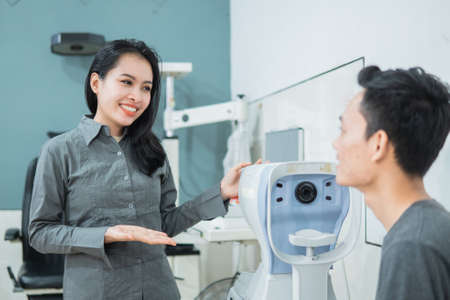 a female doctor using a device with a male patient in the examination room at the eye clinicの写真素材