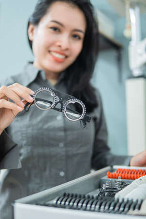a female doctor holding an eye test measuring aid in an eye clinic with the doctors backgroundの写真素材