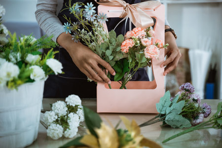 portrait florist preparing a gift flower on table workspace for customerの写真素材