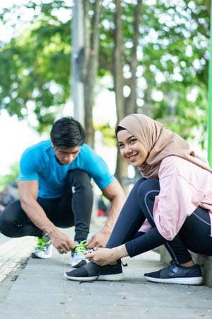 a girl in a smiling veil stares at the camera as she prepares to fix her shoelaces before jogging...