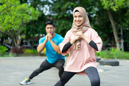hijab girls doing leg warm-up exercises together before exercising in the parkの写真素材