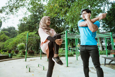Muslim couples chatting while standing doing warm-up movements before exercising in the parkの写真素材