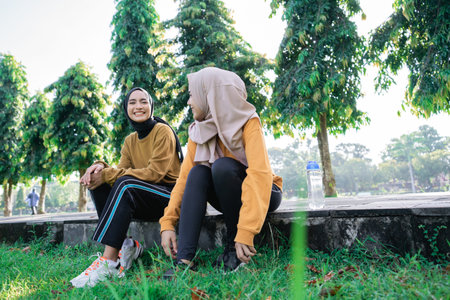 two girls wearing hijab smiling and enjoy the afternoon after exercising together in the park