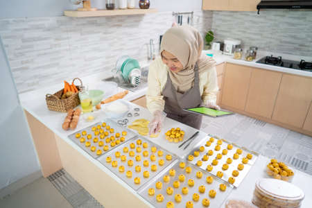portrait of happy muslim woman with nastar snack in the kitchenの写真素材