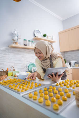 portrait of happy muslim woman with nastar snack in the kitchenの写真素材