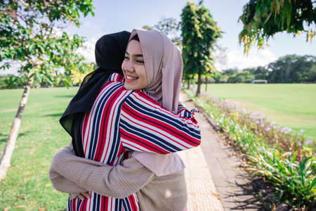 Two muslim girls hug on the sidewalk. Feel joyfull and happy together.の写真素材